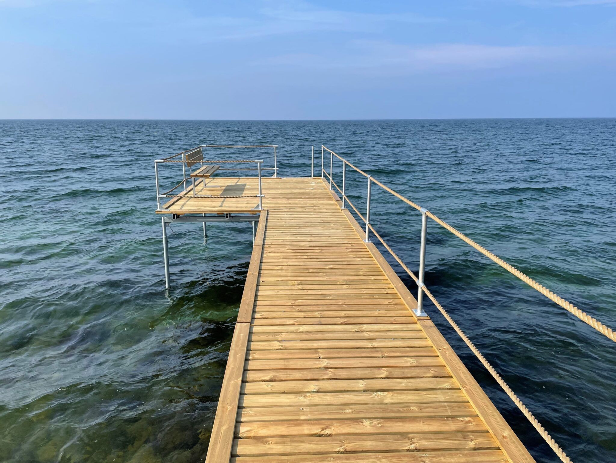 Se vores badebro fremhævet af det klare havvand og dens naturskønne omgivelser